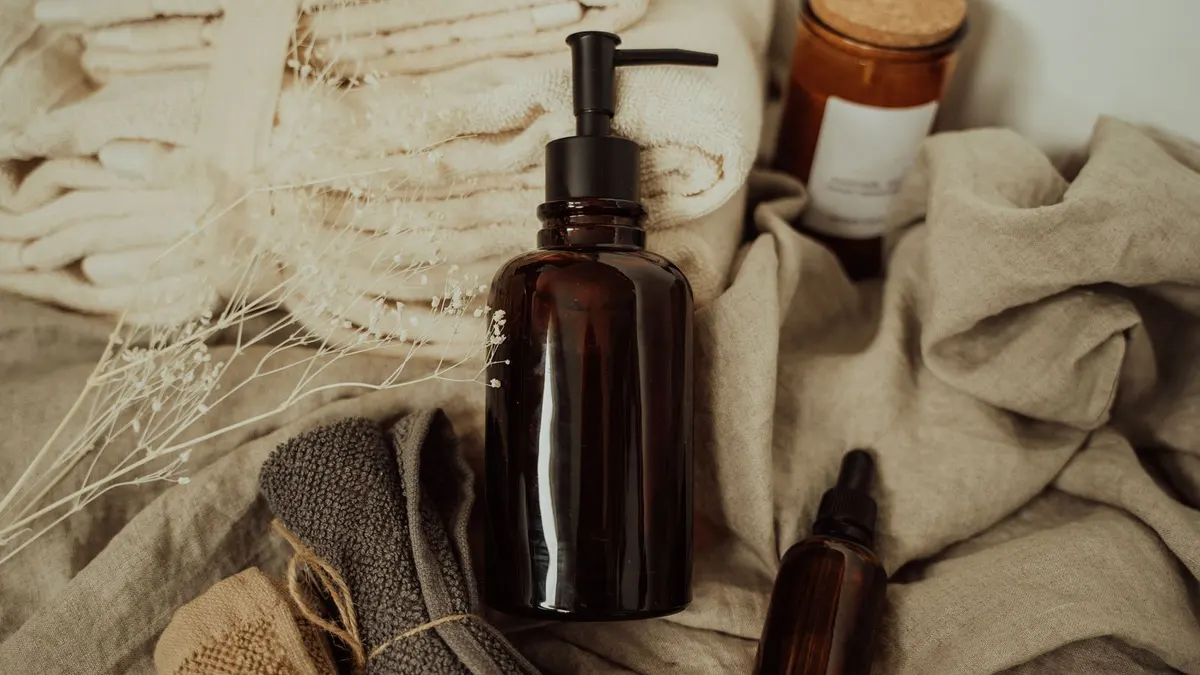 Amber glass dropper bottles on natural linen with towels in soft light