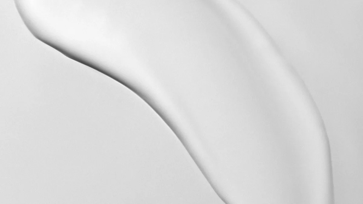 A thick sweep of rich white night cream curving across a soft grey surface