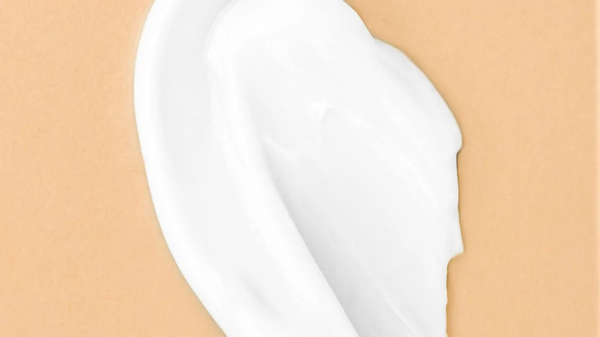 A swatch of rich white moisturizing cream smoothed across a warm tan background