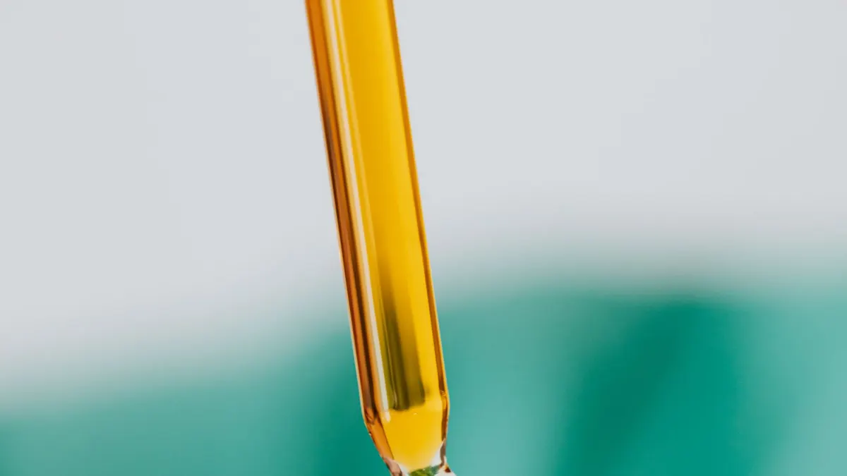 A glass dropper of golden vitamin C serum against a soft background